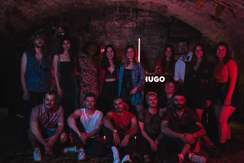 Gruppenbild vor der HUGO Neonschrift